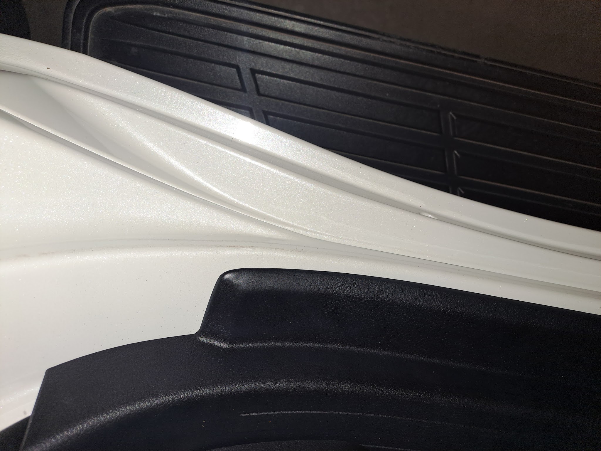 A close crop of a white vehicle panel and its body line
