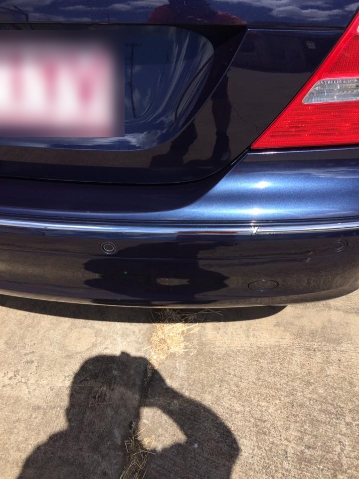 The rear bumper of a dark blue Mercedes polished to a deep, even shine