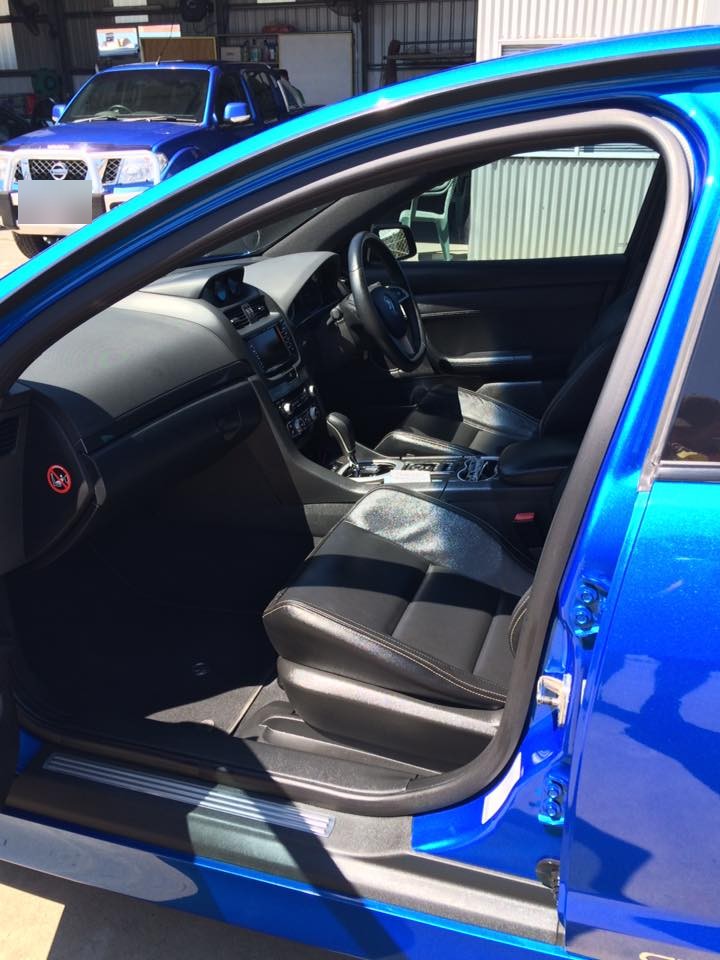 The cleaned interior of a blue Ford Falcon with the door open at the workshop