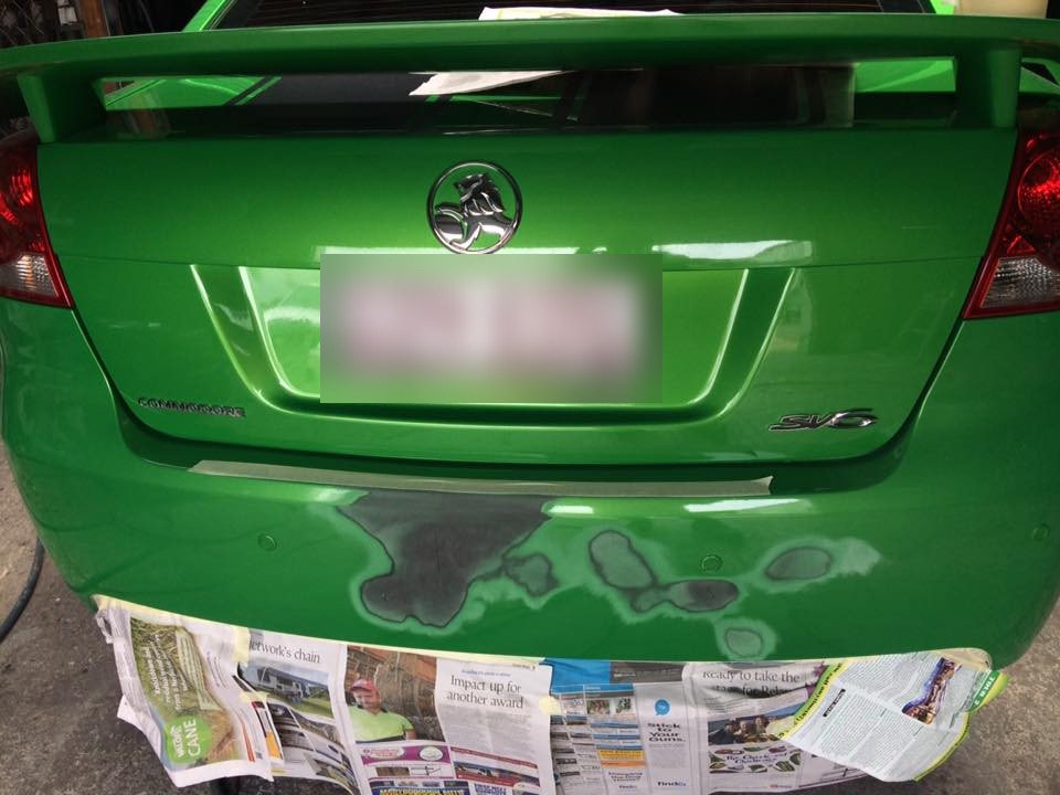 Rear bumper, green Commodore SV6: Masked up with newspaper, the repaired area still patchy in primer.